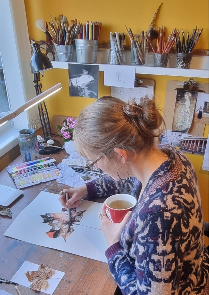 Rachel Battersby, fine artist, working at her desk in a studio